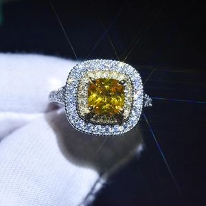 Detailed close-up of a square yellow gemstone ring with double halo diamond setting