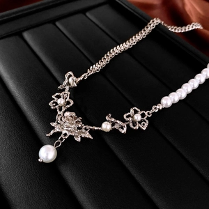 Macro view of silver rose petal detail and pearl pendant on textured leather