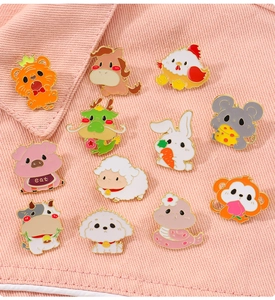 Macro view of twelve colorful zodiac animal enamel pins on a pink denim background