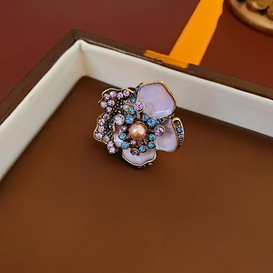 Close-up of vintage flower brooch with pink enamel petals, pearl center and crystals