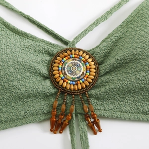 Detail of green pleated bikini top featuring bohemian beads and a retro floral ornament