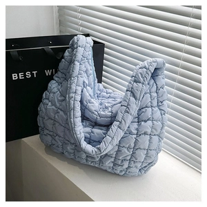 Macro detail of a light blue quilted puffer bag with textured square stitching and soft fabric