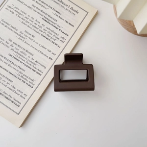 Close-up of matte dark brown square hair claw clip placed on an open book