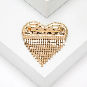 Detailed back view of golden heart brooch with secure safety pin and fringe tassels