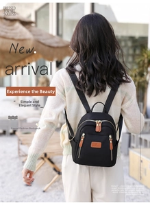 Detailed outdoor view of a black nylon mini backpack with brown leather accents and logo