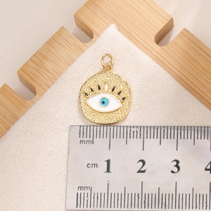 Dettaglio della misurazione di un ciondolo Evil Eye dorato da 1,8 cm con un righello