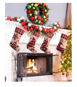 Détail de quatre chaussettes de Noël en jute avec broderie personnalisée près du foyer
