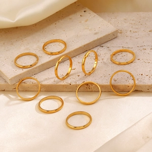 Set of minimalist gold stainless steel bands on a stone and silk background