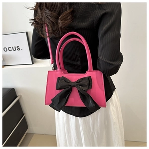 Model view of pink handbag with black satin bow showing size ratio and crossbody style