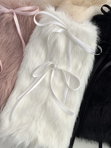 Gros plan sur les jambières en peluche rose, blanche et noire avec nœuds ruban