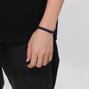 Gros plan d'un bracelet gourmette bleu en acier titane sur le poignet d'un mannequin