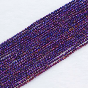 Macro shot of 2mm faceted crystal glass beads in iridescent dark purple and indigo blue