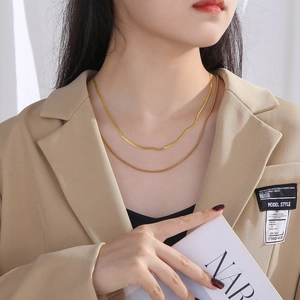 Double layered gold pearl and flat blade snake chain necklace worn by a fashion model