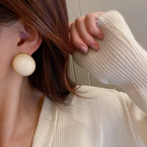Boucles d'oreilles rétro blanc crème avec bordure dorée portées par un mannequin femme