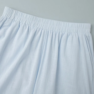 Detail of light blue cotton pants featuring an elastic waistband and breathable fabric texture