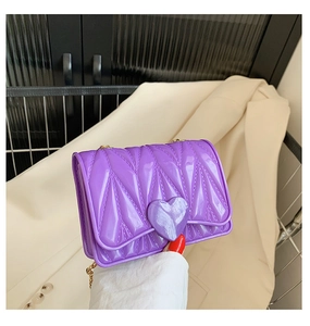 Close-up of purple patent leather mini crossbody bag with heart clasp and gold chain