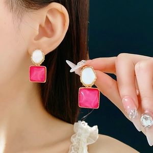 Detail von rosa und weißen geometrischen Ohrringen mit Goldrahmen am Modell