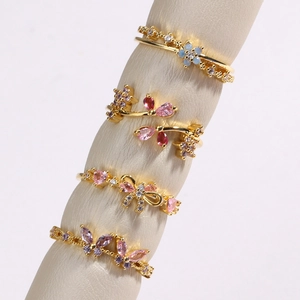 Vue détaillée de bagues fleurs et papillons avec zircons roses et mauves sur monture or