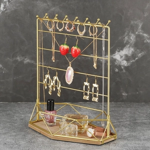 Detailed view of golden iron jewelry display rack with natural wood base on marble background