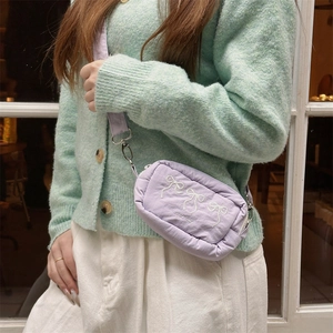 Detail of light purple crossbody bag with white bow embroidery on a model