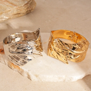 Metallic leaf-shaped open cuff bracelets in gold and silver finish on marble stone