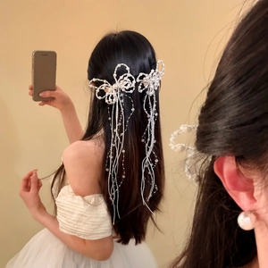 Close-up detail view of a model wearing an elegant white pearl bow tassel hair clip