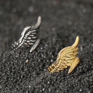 Macro shot of detailed golden angel wing ring with intricate feather texture on dark sand