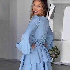 Detail of light blue dress showing puff sleeves, open back with bow tie and ruffled hem