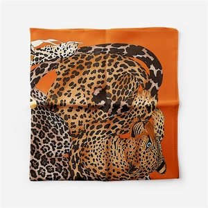 Close-up of bright orange square silk scarf with leopard print and hemmed edge details