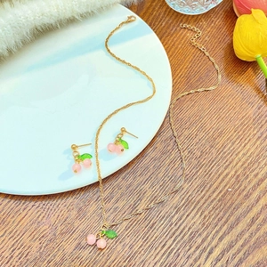 Dettaglio del set collana e orecchini a ciliegia su un vassoio di ceramica bianca