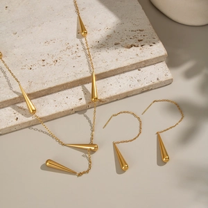 Détail de l'ensemble collier et boucles d'oreilles goutte en acier doré 18 carats