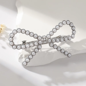 Detail of elegant bow hair clip with pearls and rhinestones on a white stone base