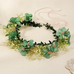 Detail of floral garland headband with pink flowers, green leaves and ribbon tie