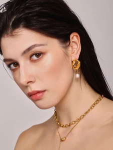 Détail d'un mannequin portant des boucles d'oreilles lave dorées et pendentifs perles