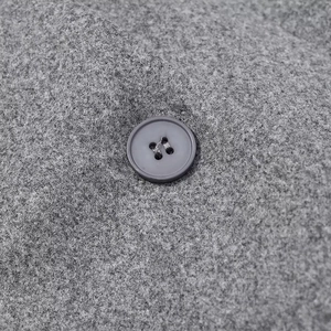 Close-up of grey wool blend fabric texture and dark round four-hole button detail
