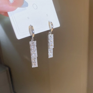 Close-up of geometric silver drop earrings featuring sparkling cubic zirconia stones