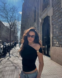 Détail d'un haut noir asymétrique ajusté avec un jean bleu dans un style urbain chic