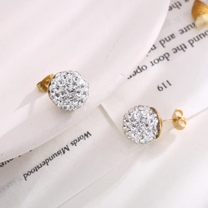 Détail de boucles d'oreilles boules en cristal étincelant sur une assiette blanche