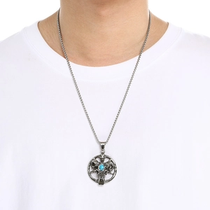 Detail der silbernen Widderkopf-Halskette mit blauem Edelstein auf weißem T-Shirt