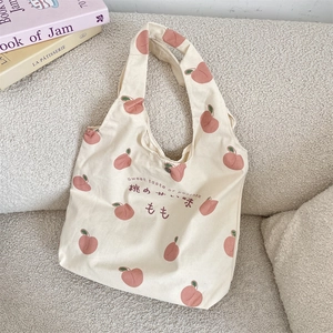 Detail of peach print and Japanese text on the cream canvas tote bag surface