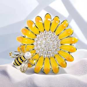 Enamel sunflower brooch with crystal center and pearl bee accent on grey textile