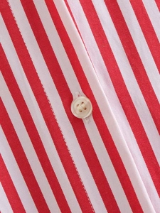 Macro detail of red and white striped poplin shirt with white resin button stitching