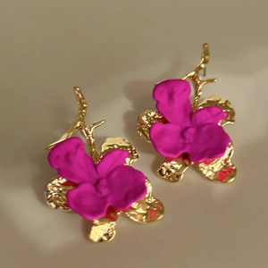 Detailed macro view of magenta orchid flower earrings with elegant gold branch-like metal base