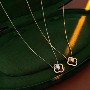 Detailed view of silver and gold flower petal necklaces in a green velvet jewelry box