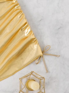 Macro shot of gold metallic bikini fabric with drawstrings and side tie ribbons