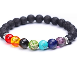 Lava stone chakra bracelet with seven colorful natural beads and metal spacers on white back