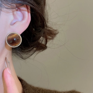Close-up of 18k gold-plated round tiger eye stone earring worn by a model
