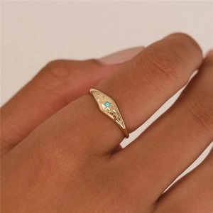 Detailed view of gold S925 ring with engraved star and turquoise stone on model's finger
