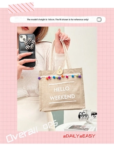 Detail of bohemian linen tote with colorful pom poms, lace trim and Hello Weekend text