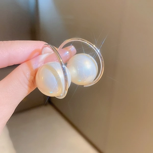 Macro shot of silver C-shaped pearl earring featuring a large white bead with starburst light